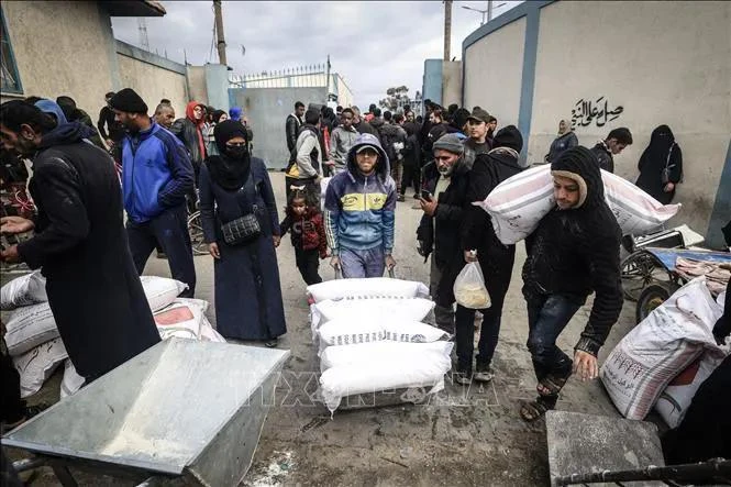 Refugiados palestinos reciben ayuda de la Agencia de Naciones Unidas para la población refugiada de Palestina en Oriente Próximo (UNRWA) en la ciudad de Rafah, Franja de Gaza. (Foto: AFP/VNA)