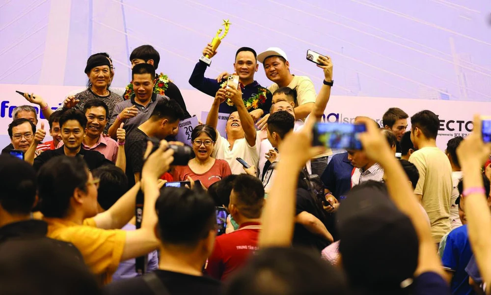 Brandissant le trophée de la Coupe du monde de billard carambole à trois bandes, Trân Duc Minh est entouré de ses fans. Photo : CTV/CVN