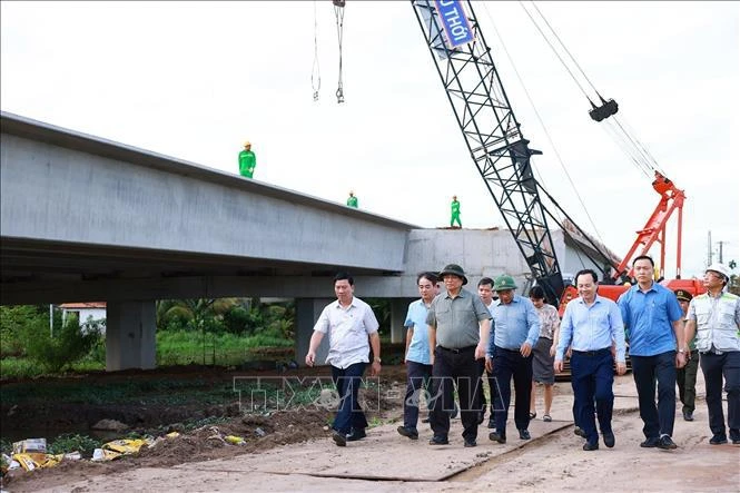 Le PM Pham Minh Chinh (troisième à partir de la gauche) et des responsables examinent le chantier de construction du tronçon de l’autoroute Cân Tho-Cà Mau dans la province de Hâu Giang, le 12 juillet. Photo : VNA