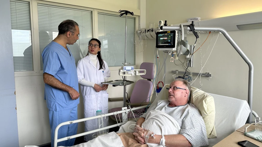 Jacques Ballout, chef du service de cardiologie de l’hôpital Pierre-Bérégovoy, et une stagiaire vietnamienne au chevet d’un patient français. Photo : VNA