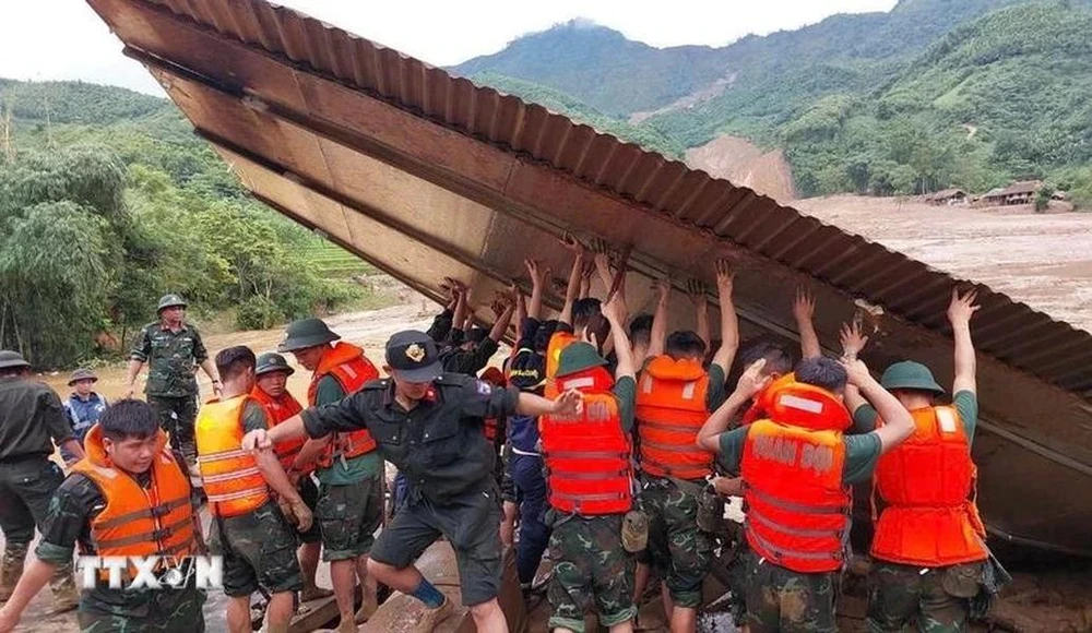 Des secouristes recherchent des personnes dans des maisons effondrées à la suite d’un glissement de terrain causé par de fortes pluies. Photo: VNA