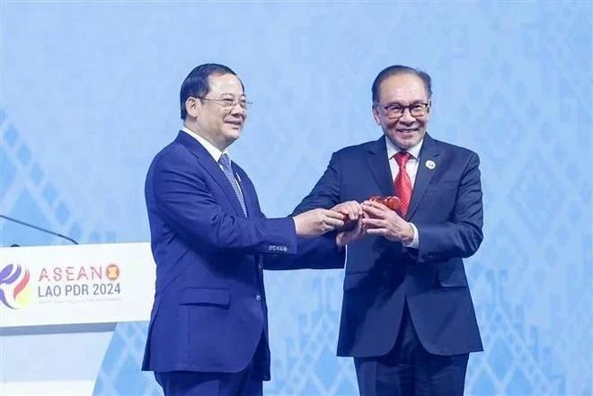 Le Premier ministre malaisien Anwar bin Ibrahim (à droite) reçoit le marteau de la présidence de l'ASEAN des mains du Premier ministre lao Sonexay Siphandone, à Vientiane, le 11 octobre. Photo : VNA