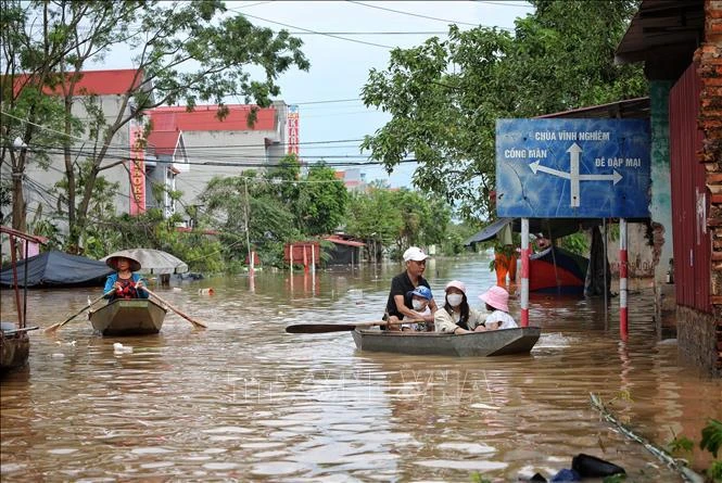 Les habitants de la commune Tri Yen, district de Yên Dung, province de Bac Giang empruntent des barques pour traverser une route inondée, le 13 septembre 2024. Photo : VNA