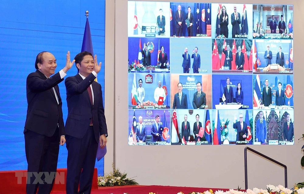 Vietnamese Prime Minister Nguyen Xuan Phuc (left) and Minister of Industry and Trade Tran Tuan Anh, together with leaders of other RCEP member countries, witness the pact signing via videoconference on November 15 (Photo: VNA)