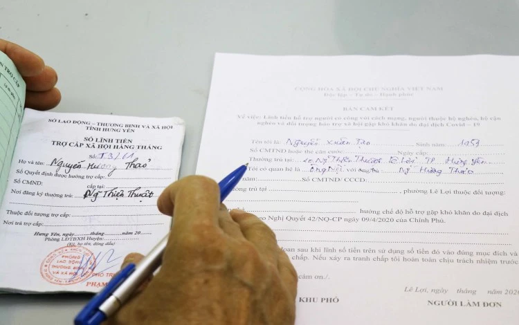 People filling out forms to receive support from the relief package (Photo: VNA)