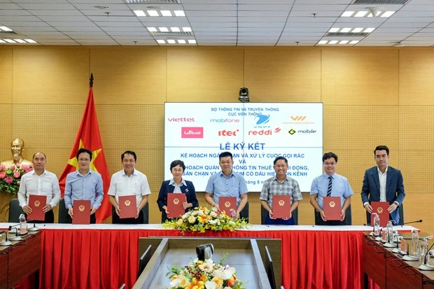 Representatives of Vietnamese mobile network operators – Viettel, VNPT, MobiFone, Vietnammobile, Local, Reddi, Itel, and GMobile – sign an agreement to fight spam calls jointly. (Photo: VietnamPlus)