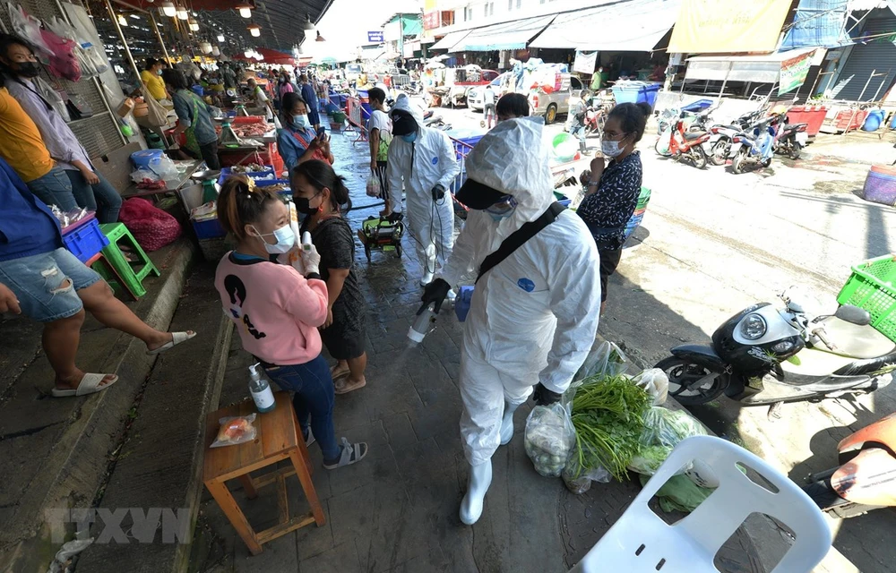 Staff spray disinfectant in a market in Samut Sakhon province, Thailand, December 21, 2020. (Photo: Xinhua/VNA)