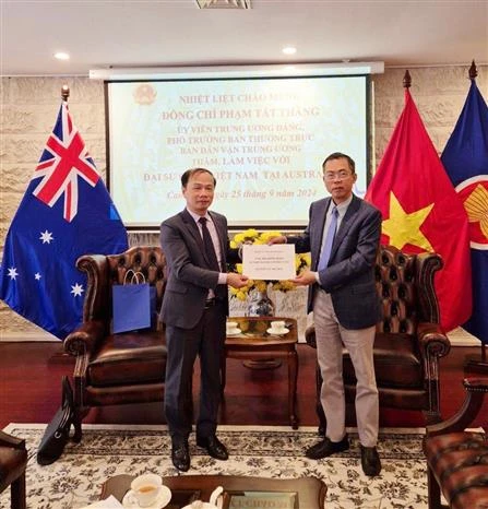 Ambassador Pham Hung Tam (R) hands over 12,700 AUD (8,700 USD) to the delegation to help victims of Typhoon Yagi (Photo: VNA)