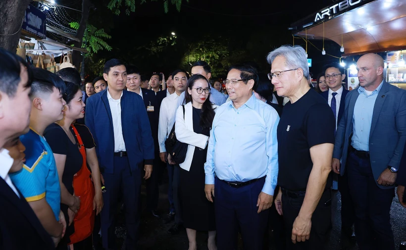 Vietnamese Prime Minister Pham Minh Chinh (third, right), and President and CEO of NVIDIA Jensen Huang (second, right) talk with local residents and visitors in Hanoi on December 5 night. (Photo: VNA)